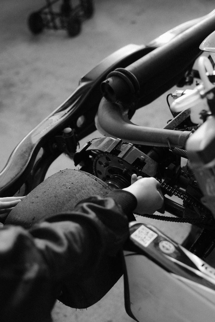 Monochrome close-up of hands adjusting a go-kart engine, ideal for mechanical or automotive themes.