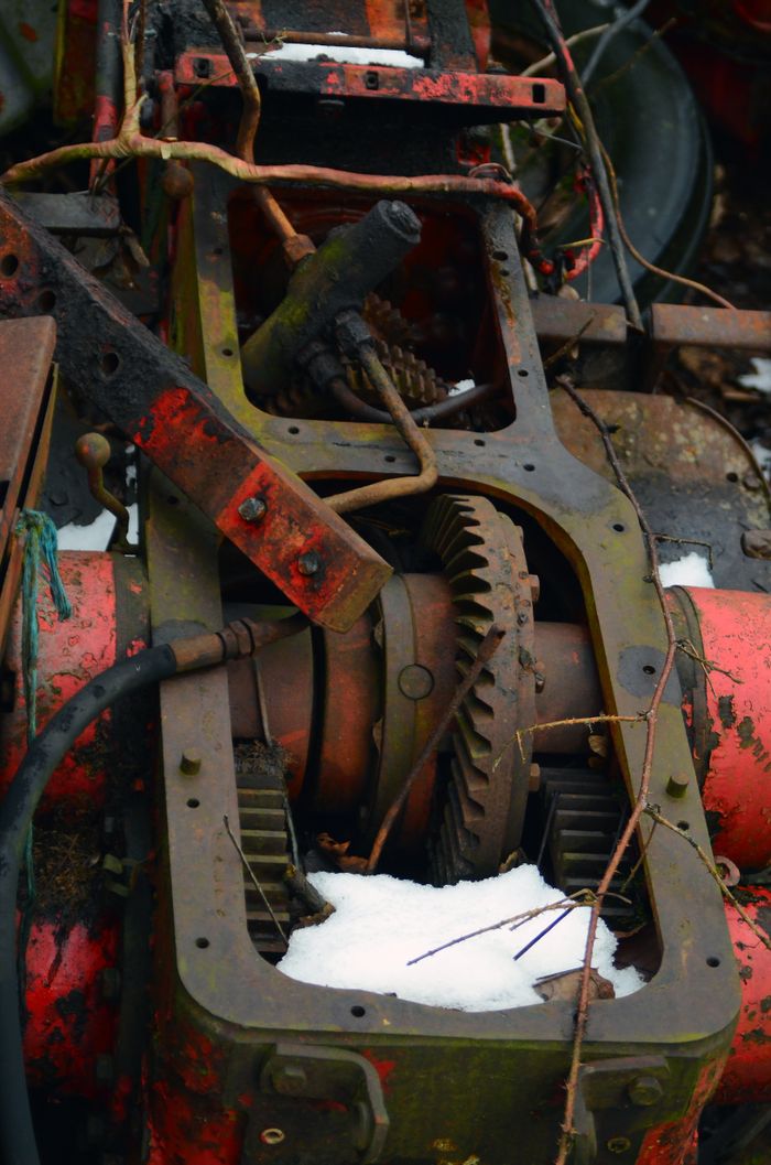 about-01 Close-up view of rusty industrial machinery with gears, partially covered in snow, depicting decay.